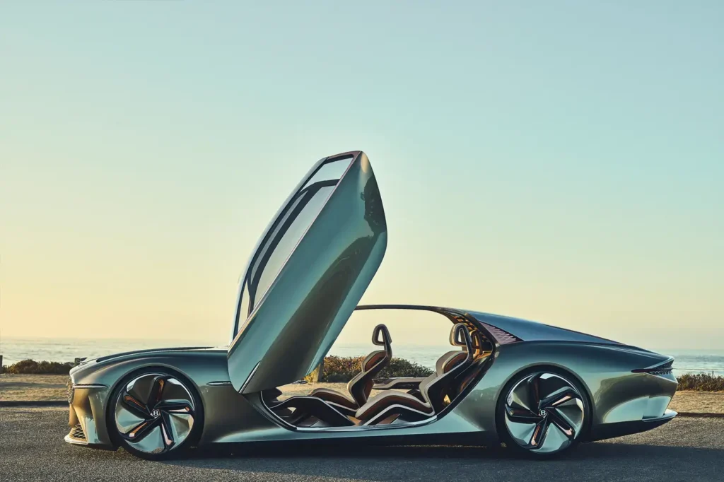 La première voiture 100% électrique Bentley, model  EXP 100 GT cabriolet - retardé d'un an - date de sortie prévue en 2026. Photo 
en 3 D intérieur cuir ton beige, brun-porte ouverte et toi décapoté-fond ciel bleu- Vue de profil de toute la voiture