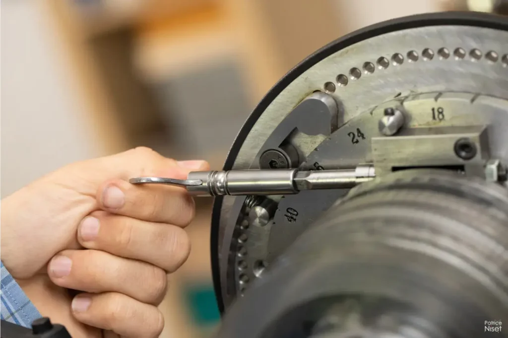 montre de poche-Miroir de l'ombre-Main qui règle une machine-dans un atelier de montre de poche