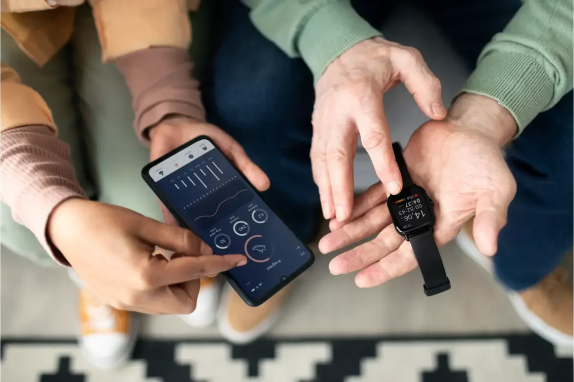 femme-arabe-apprenant-a-un-homme-age-a-utiliser-une-montre-intelligente-avec-un-smartphone