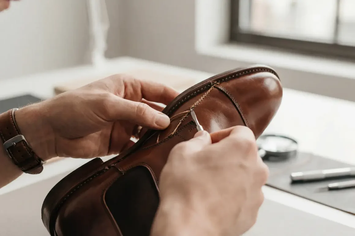Gros plan sur des mains expertes examinant la qualité d'une couture de chaussure